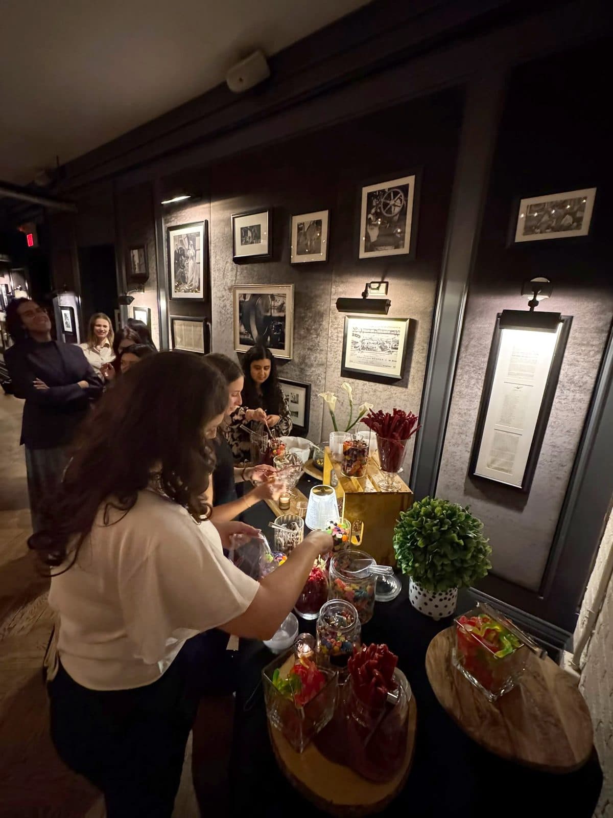 Guests filling bowls at the candy bar along the gallery wall of framed prints.