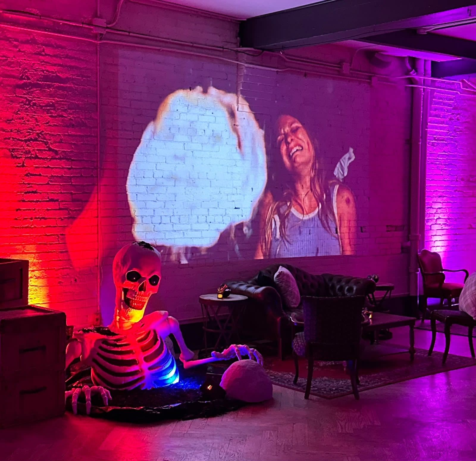 A giant skeleton pulling itself out of the floor in front of crates, a film projected across the white brick wall behind, and leather chesterfield sofas in the lounge.