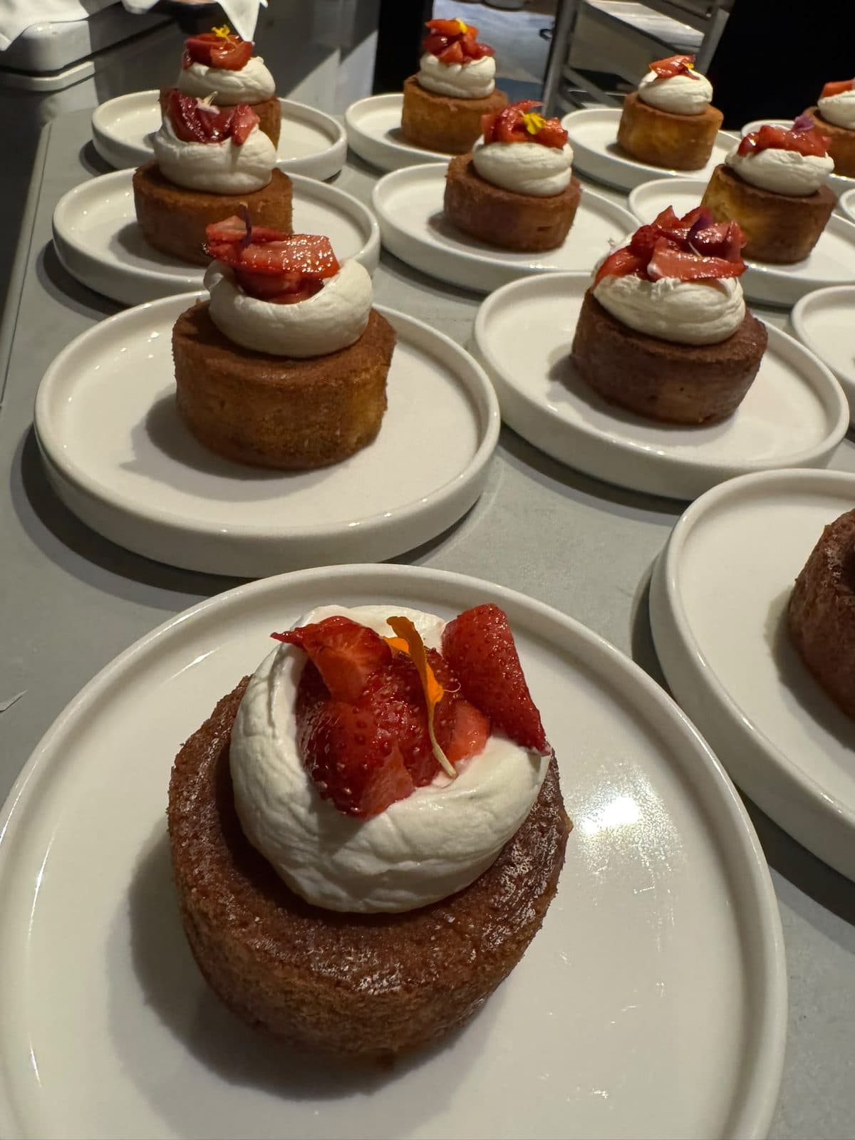 Plated semolina and coconut cakes, each topped with whipped yogurt and sliced strawberries.