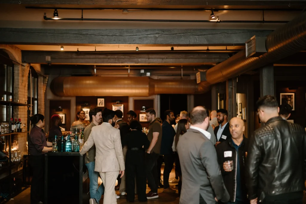 Professionals mingling at a stylish corporate networking event in a modern bar lounge setup, hosted by an event management company.