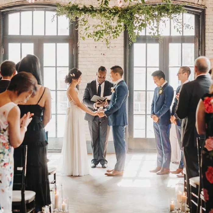 Indoor wedding ceremony with couple exchanging vows under greenery installation at Storys venue in Toronto
