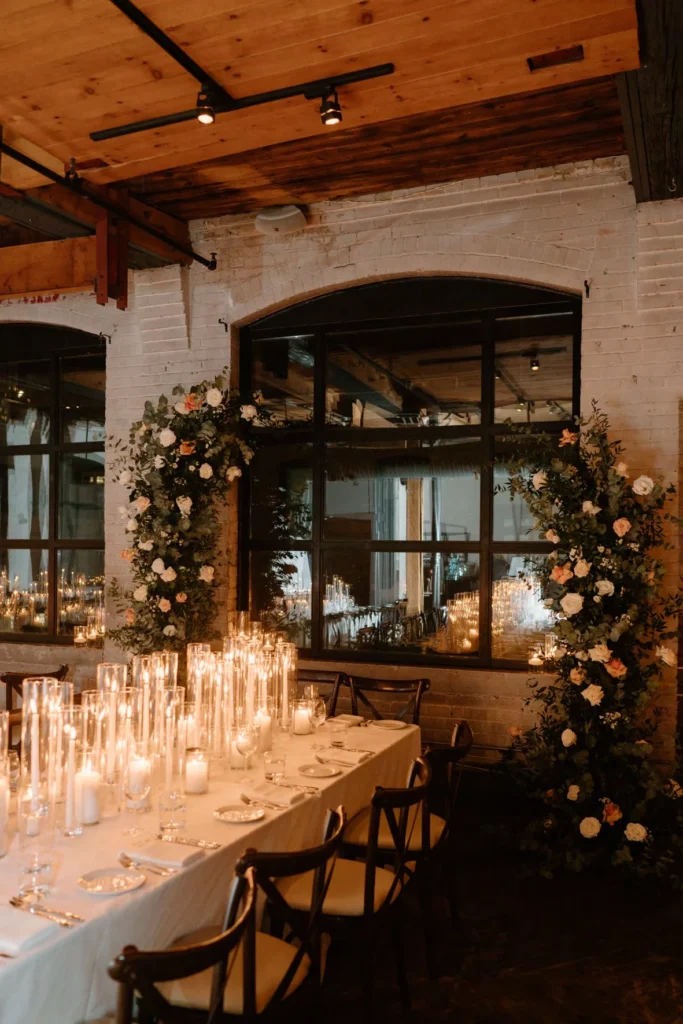 Candlelit wedding dinner setup with floral arch and rustic venue details, suited for weddings and small gatherings.